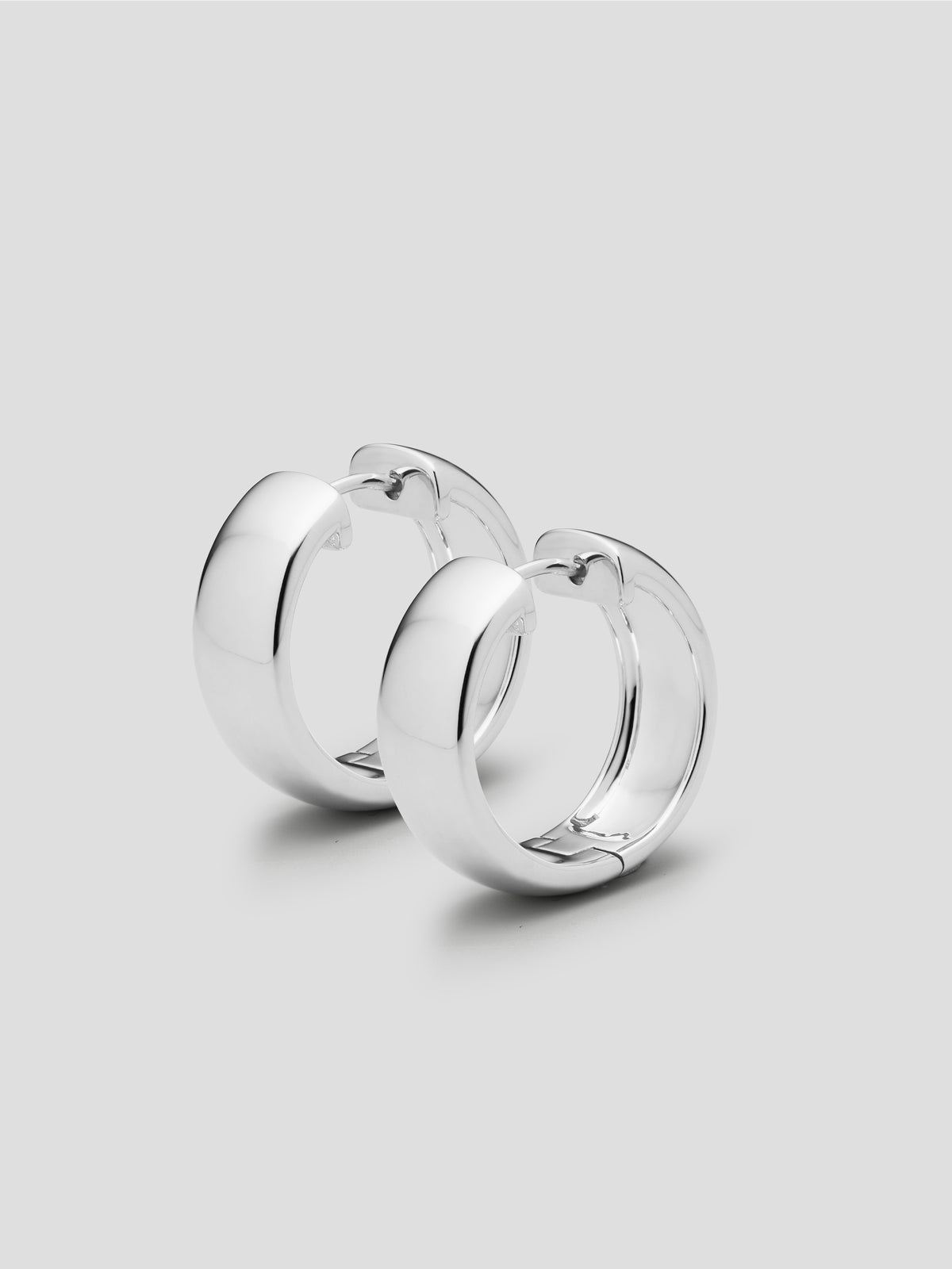A pair of silver hoop earrings on a light gray background.