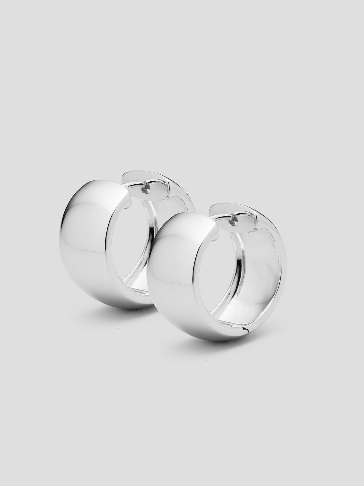 A pair of silver hoop earrings on a light gray background.